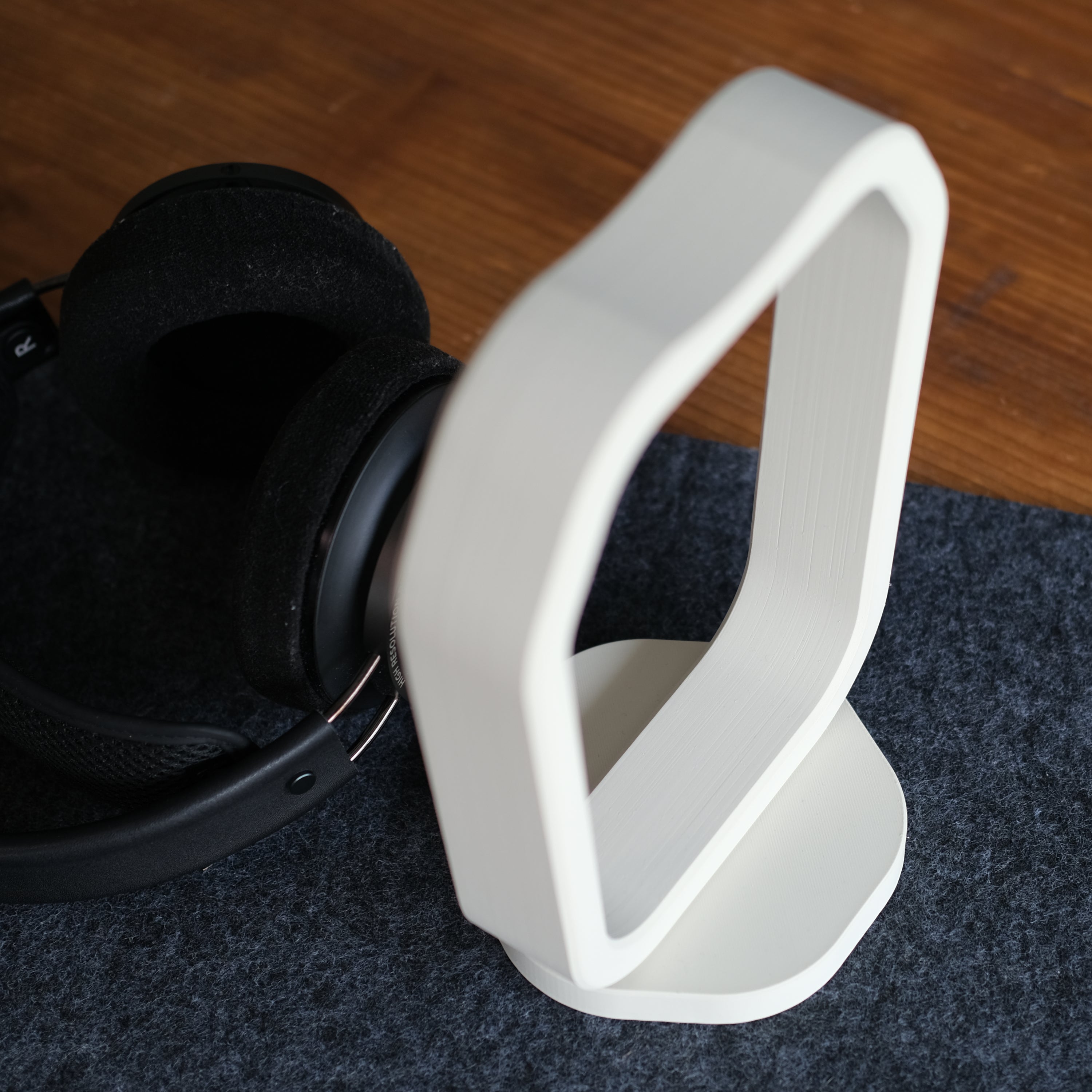 Headphone Display Stand showcasing a sleek design, paired with black headphones on a modern desk setup.